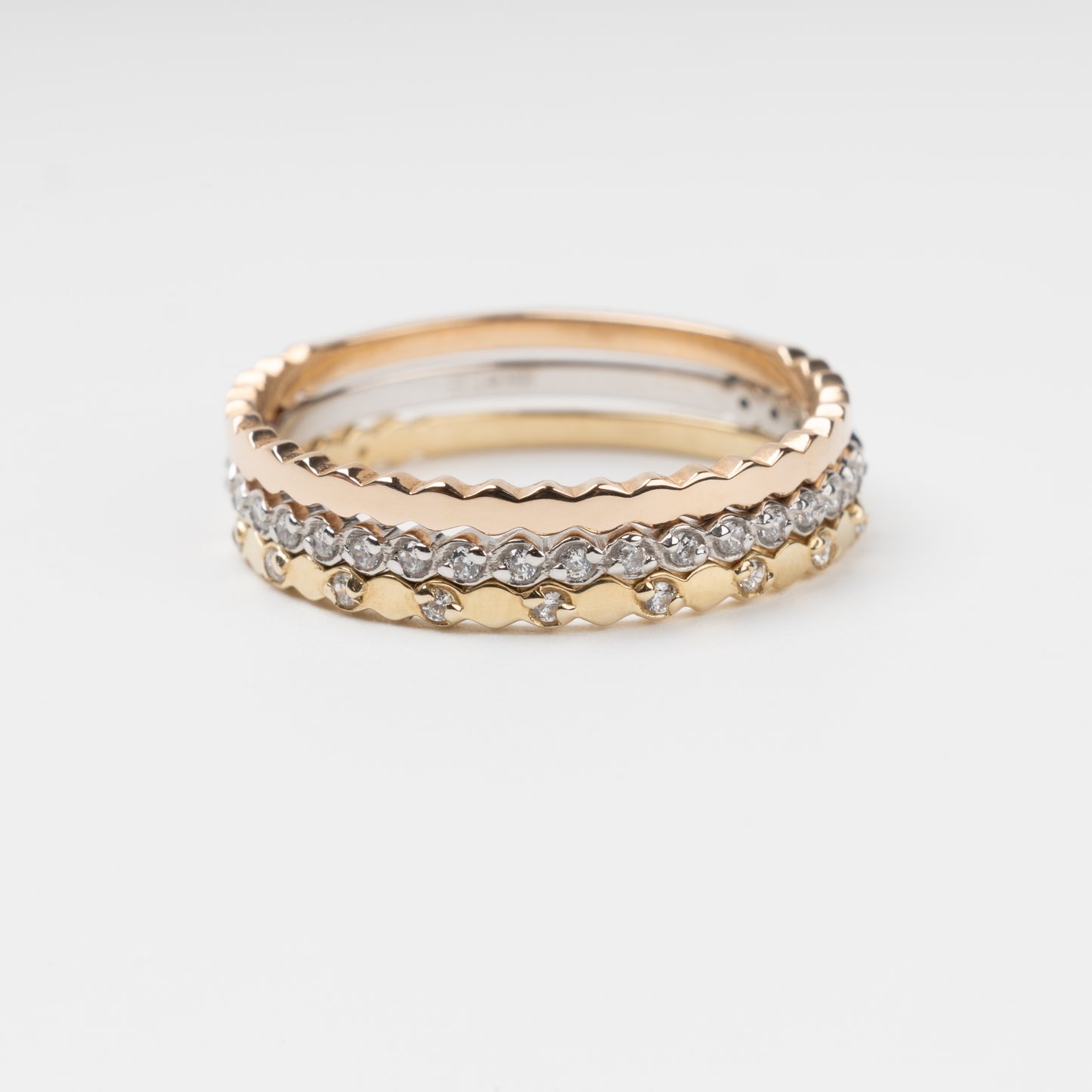 Sophisticated triple stackable ring set in 14K (585) multi-tone gold, featuring a central eternity band of clear zirconias White Gold between two uniquely scalloped Rose and Yellow Gold bands, displayed on a clean white background.