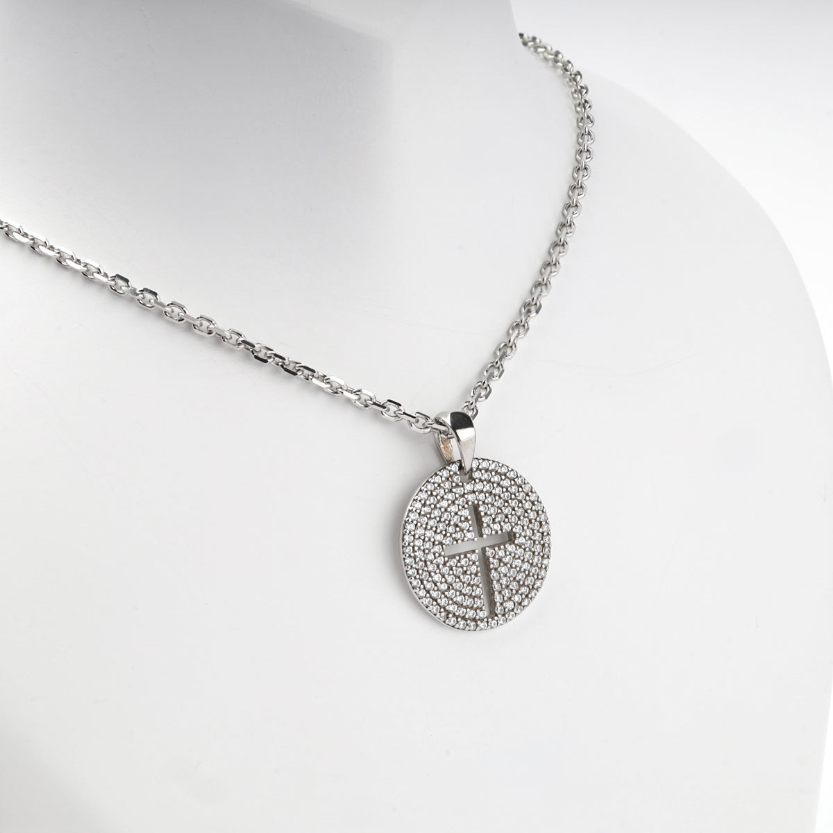 Rhodium-plated silver 925 round cross pendant with clear cubic zirconia, angled view