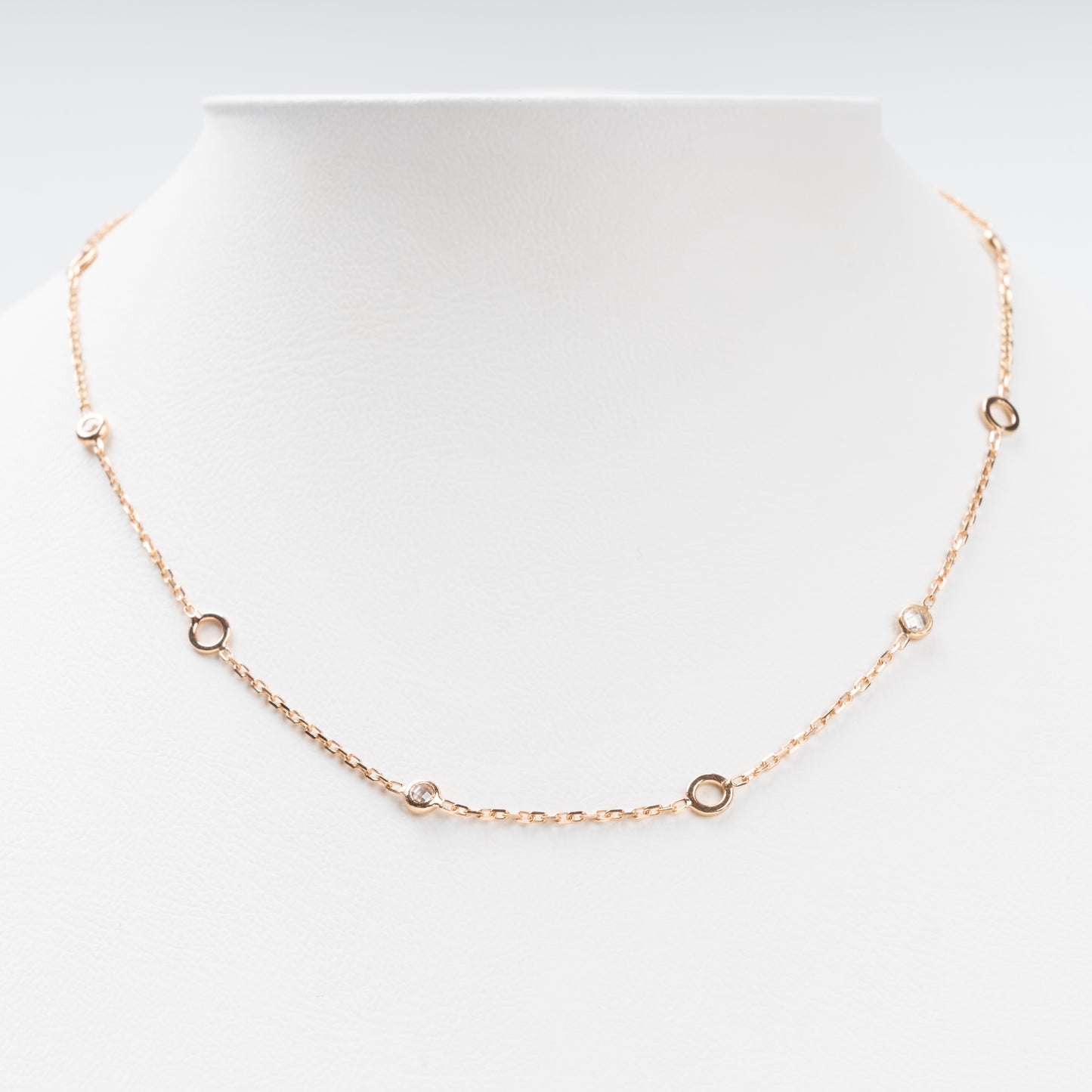 Sophisticated 14K (585) Rose Gold station necklace featuring alternating open round gold links and small bezel-set clear zirconias on a delicate chain, displayed on a white jewelry bust.