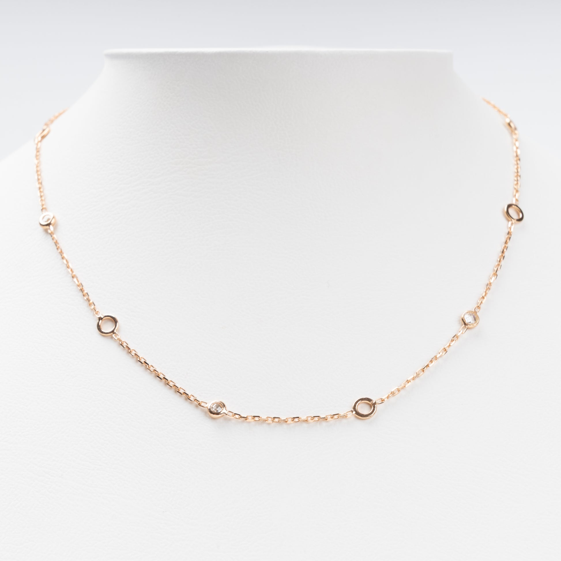 Sophisticated 14K (585) Rose Gold station necklace featuring alternating open round gold links and small bezel-set clear zirconias on a delicate chain, displayed on a white jewelry bust.