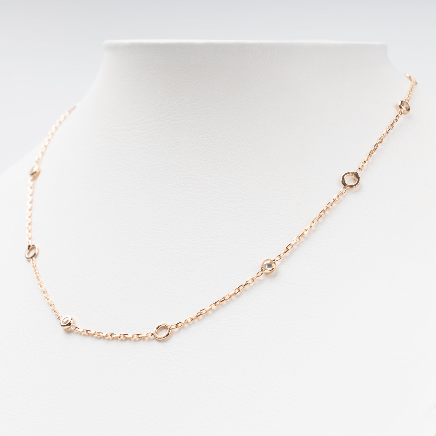 Sophisticated 14K (585) Rose Gold station necklace featuring alternating open round gold links and small bezel-set clear zirconias on a delicate chain, displayed on a white jewelry bust.