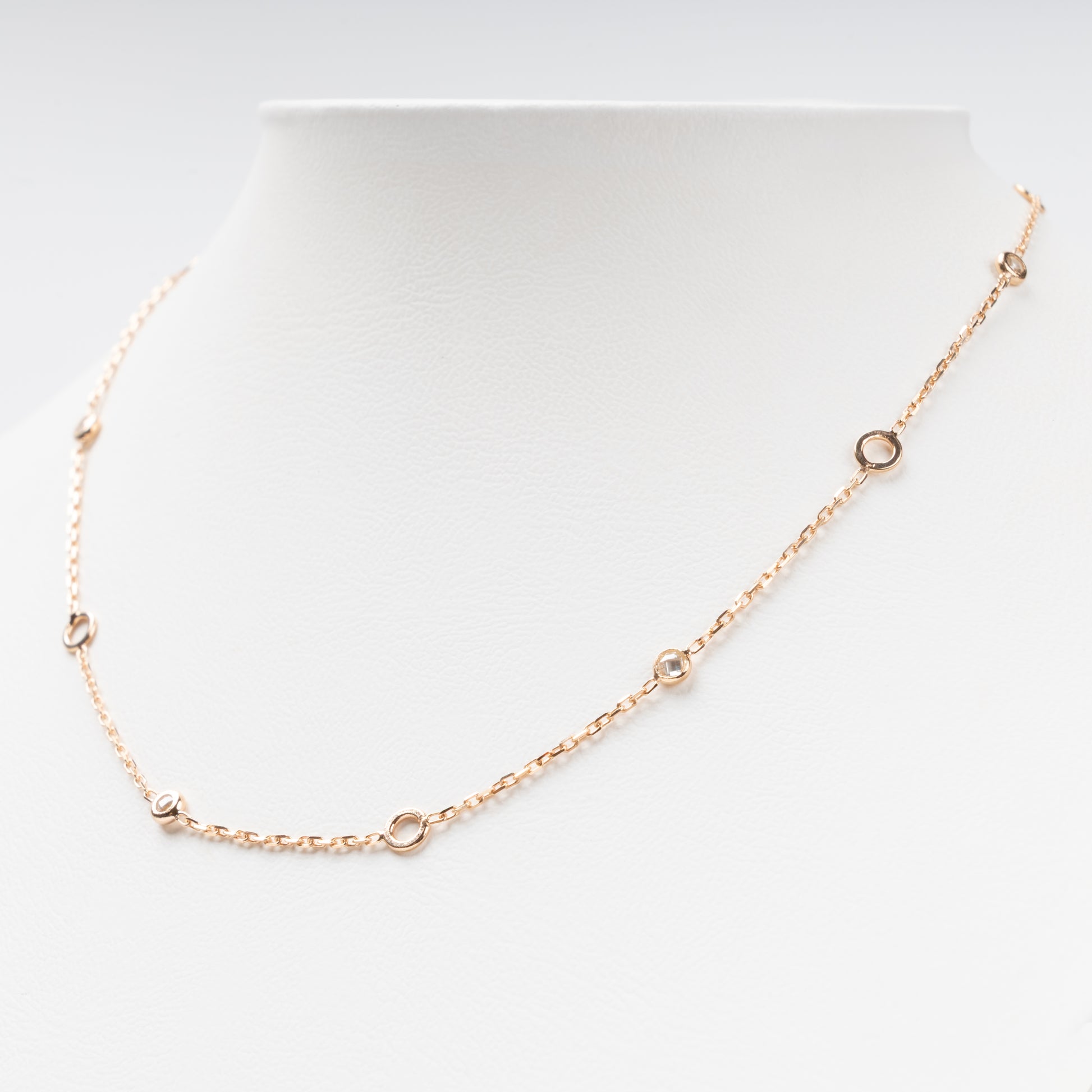 Sophisticated 14K (585) Rose Gold station necklace featuring alternating open round gold links and small bezel-set clear zirconias on a delicate chain, displayed on a white jewelry bust.
