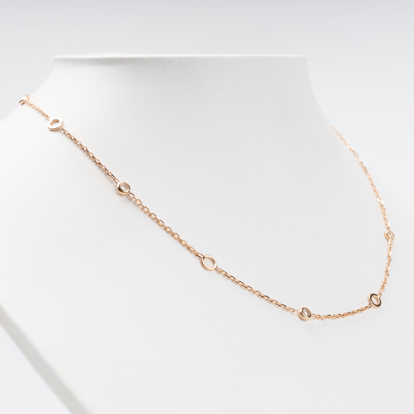 Sophisticated 14K (585) Rose Gold station necklace featuring alternating open round gold links and small bezel-set clear zirconias on a delicate chain, displayed on a white jewelry bust.