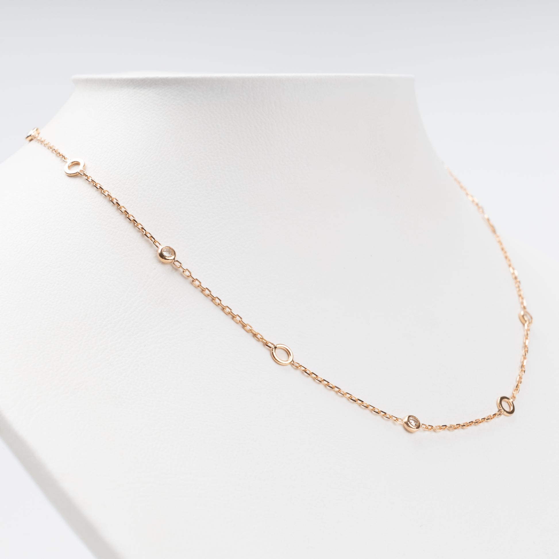 Sophisticated 14K (585) Rose Gold station necklace featuring alternating open round gold links and small bezel-set clear zirconias on a delicate chain, displayed on a white jewelry bust.