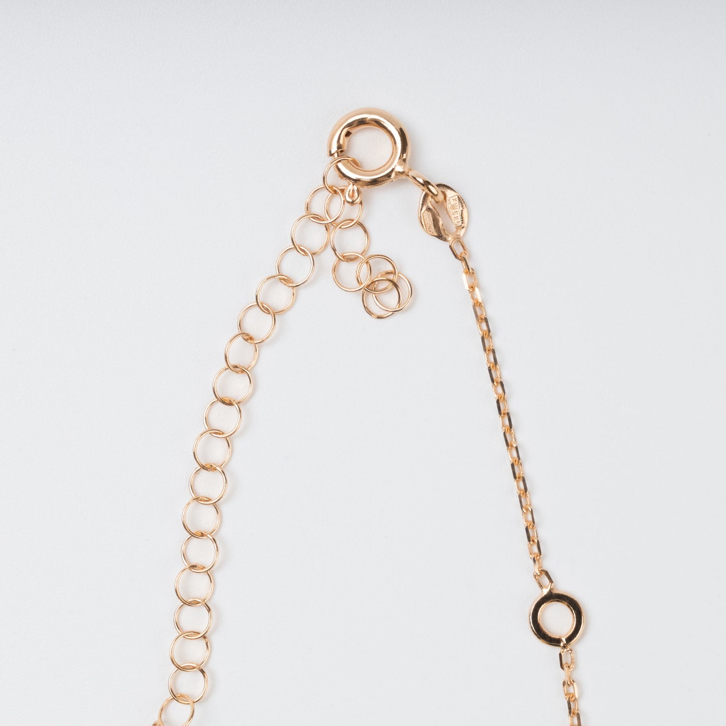Close-up view of the secure spring-ring clasp, hallmark tag, and adjustable extension chain on a 14K (585) Rose Gold necklace against a plain background.
