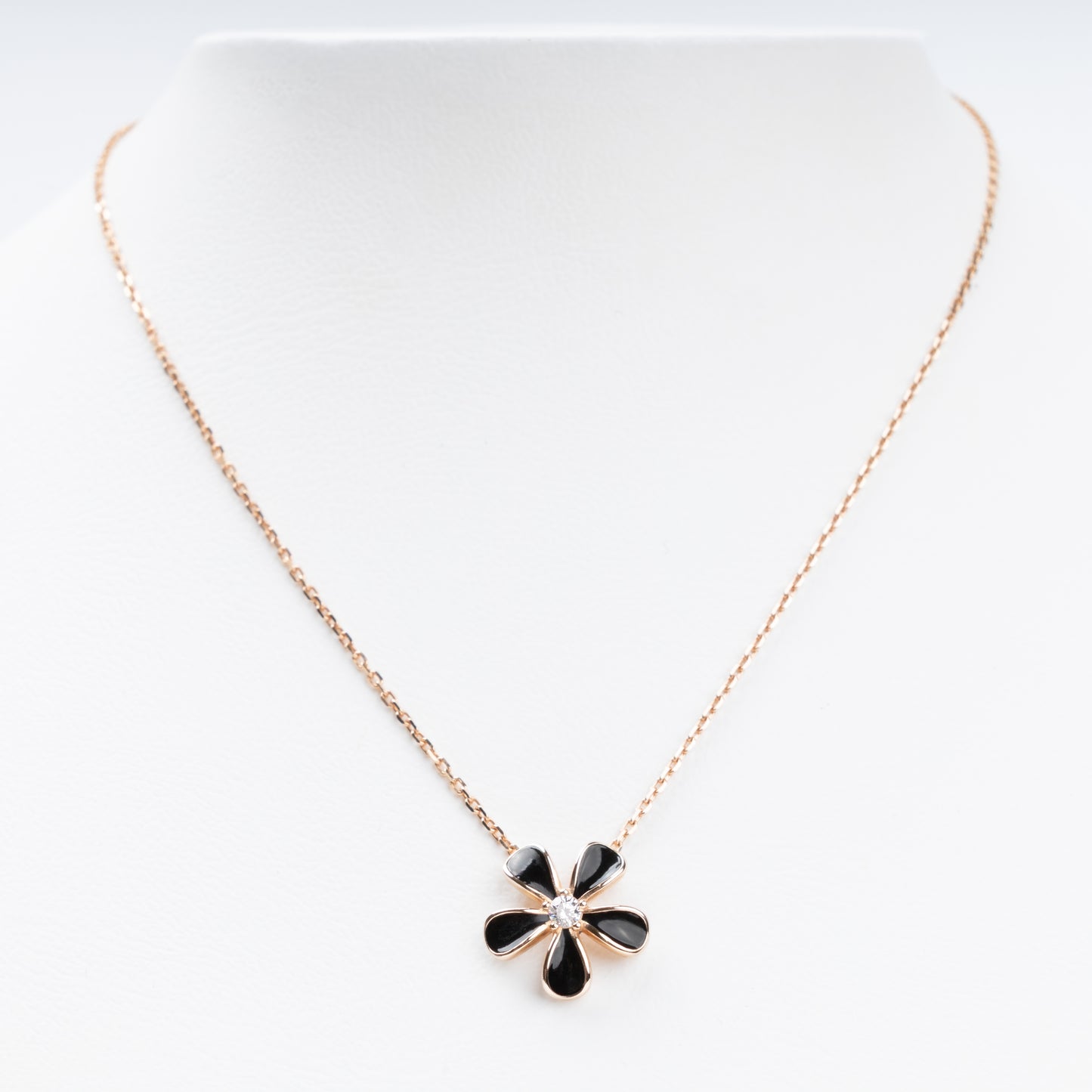 Sophisticated 14K (585) Rose Gold necklace featuring a five-petal flower pendant with black enamel inlays and a brilliant-cut zirconia center, displayed on a white jewelry bust.