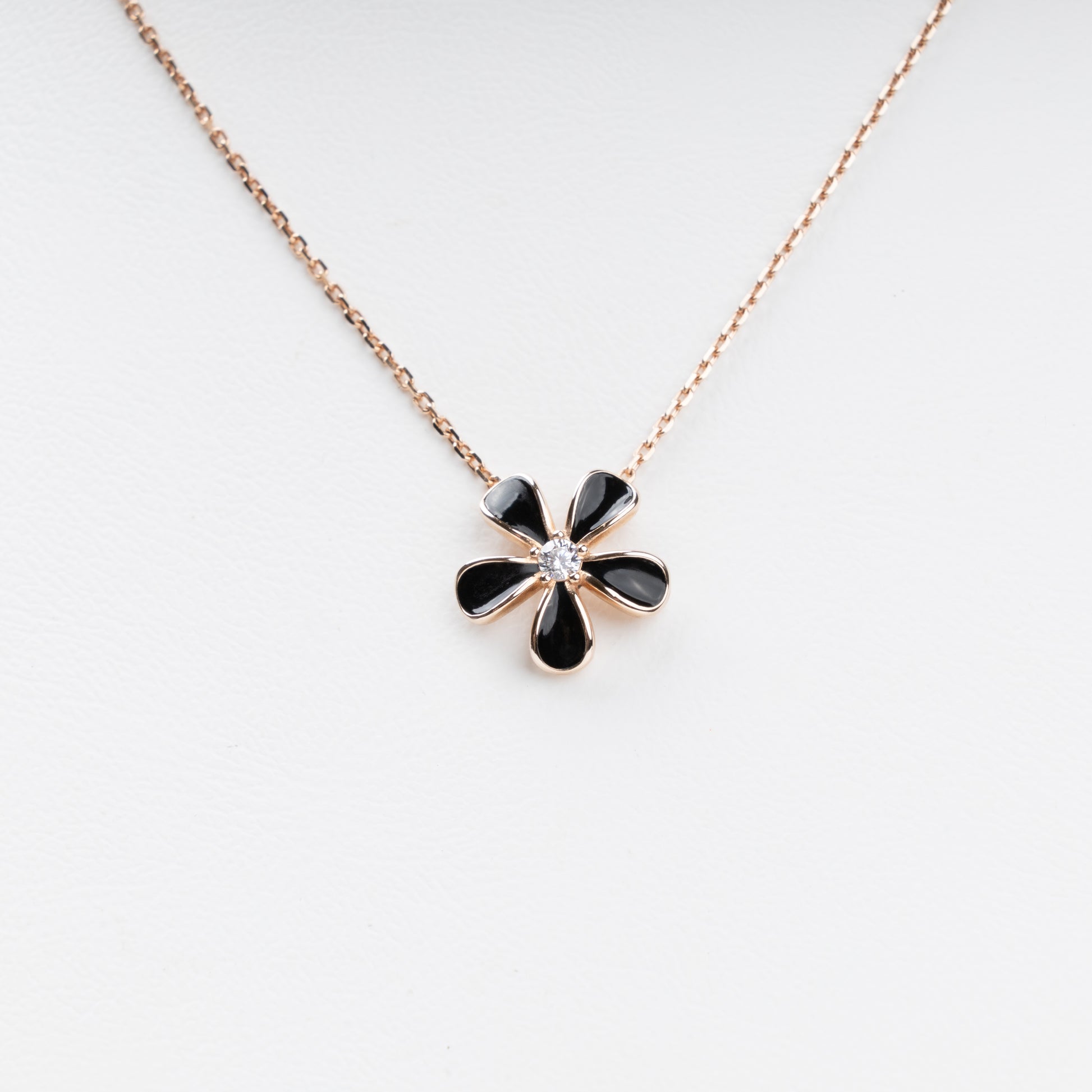 Sophisticated 14K (585) Rose Gold necklace featuring a five-petal flower pendant with black enamel inlays and a brilliant-cut zirconia center, displayed on a white jewelry bust.