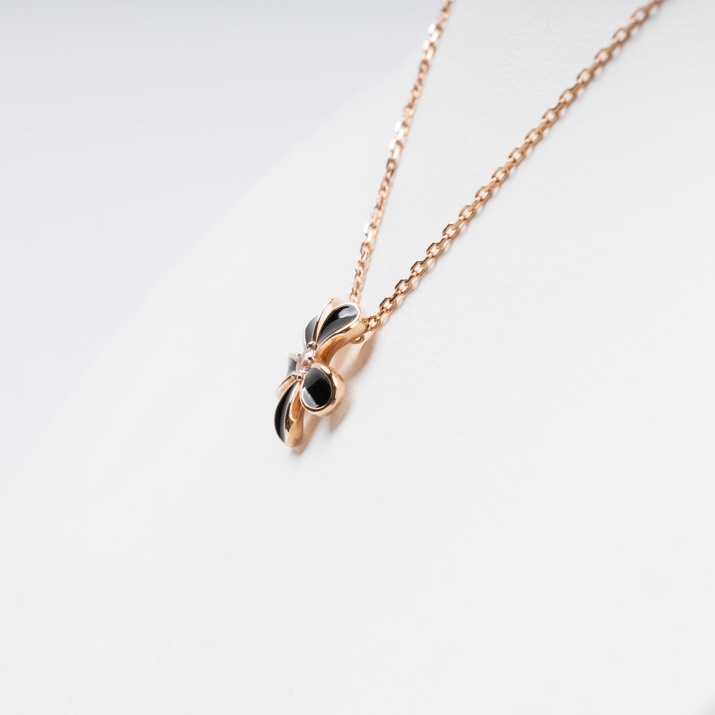 Sophisticated 14K (585) Rose Gold necklace featuring a five-petal flower pendant with black enamel inlays and a brilliant-cut zirconia center, displayed on a white jewelry bust.