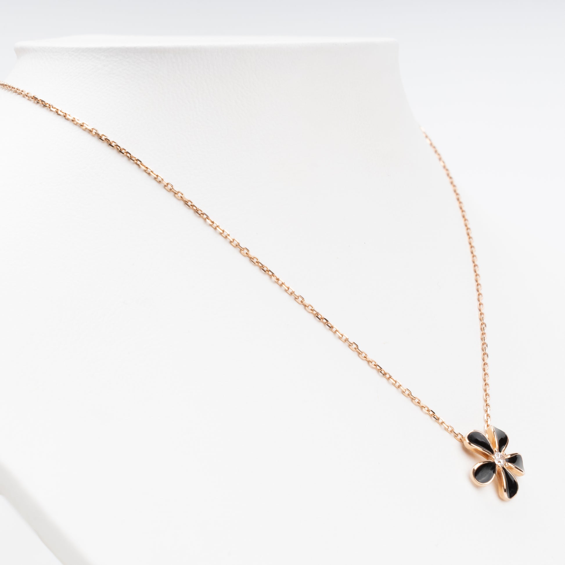 Sophisticated 14K (585) Rose Gold necklace featuring a five-petal flower pendant with black enamel inlays and a brilliant-cut zirconia center, displayed on a white jewelry bust.