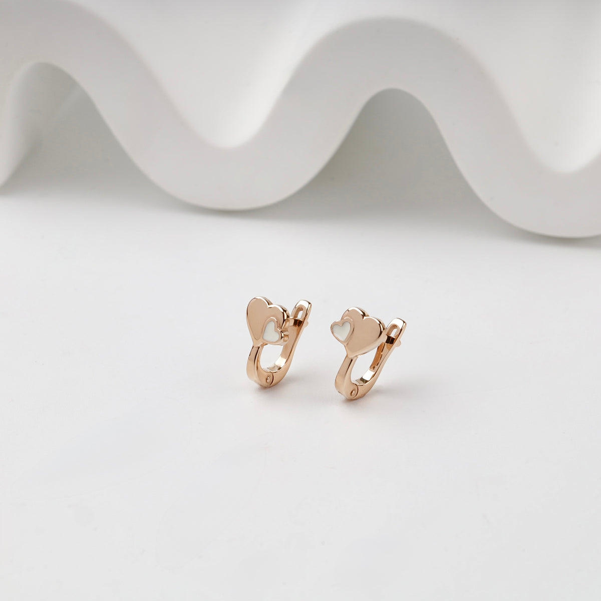 Rose Gold double heart kids earrings with white enamel, angled pair