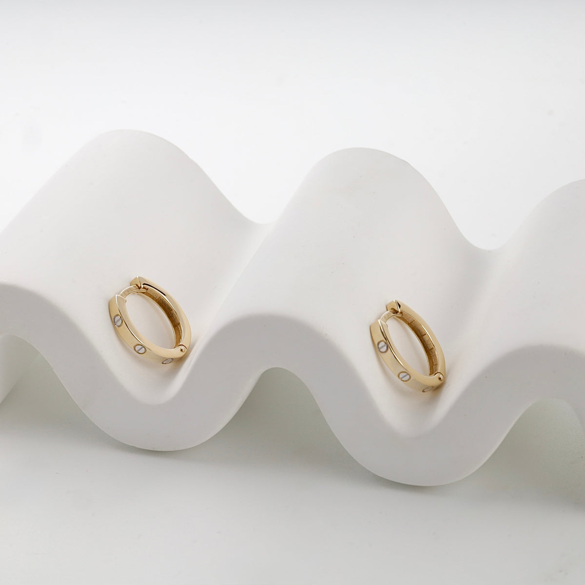 Yellow gold 585 screw motif huggie earrings on display — Kabluchka