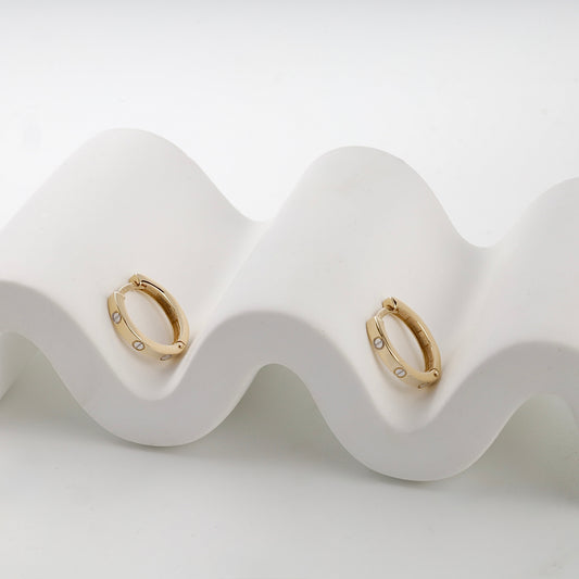 Yellow gold 585 screw motif huggie earrings on display — Kabluchka