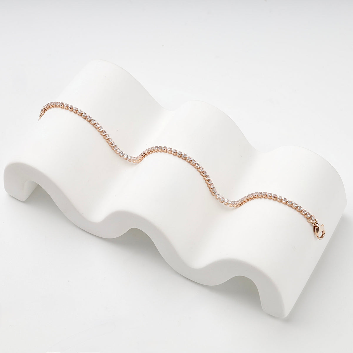 Rose gold tennis bracelet displayed in a flowing line