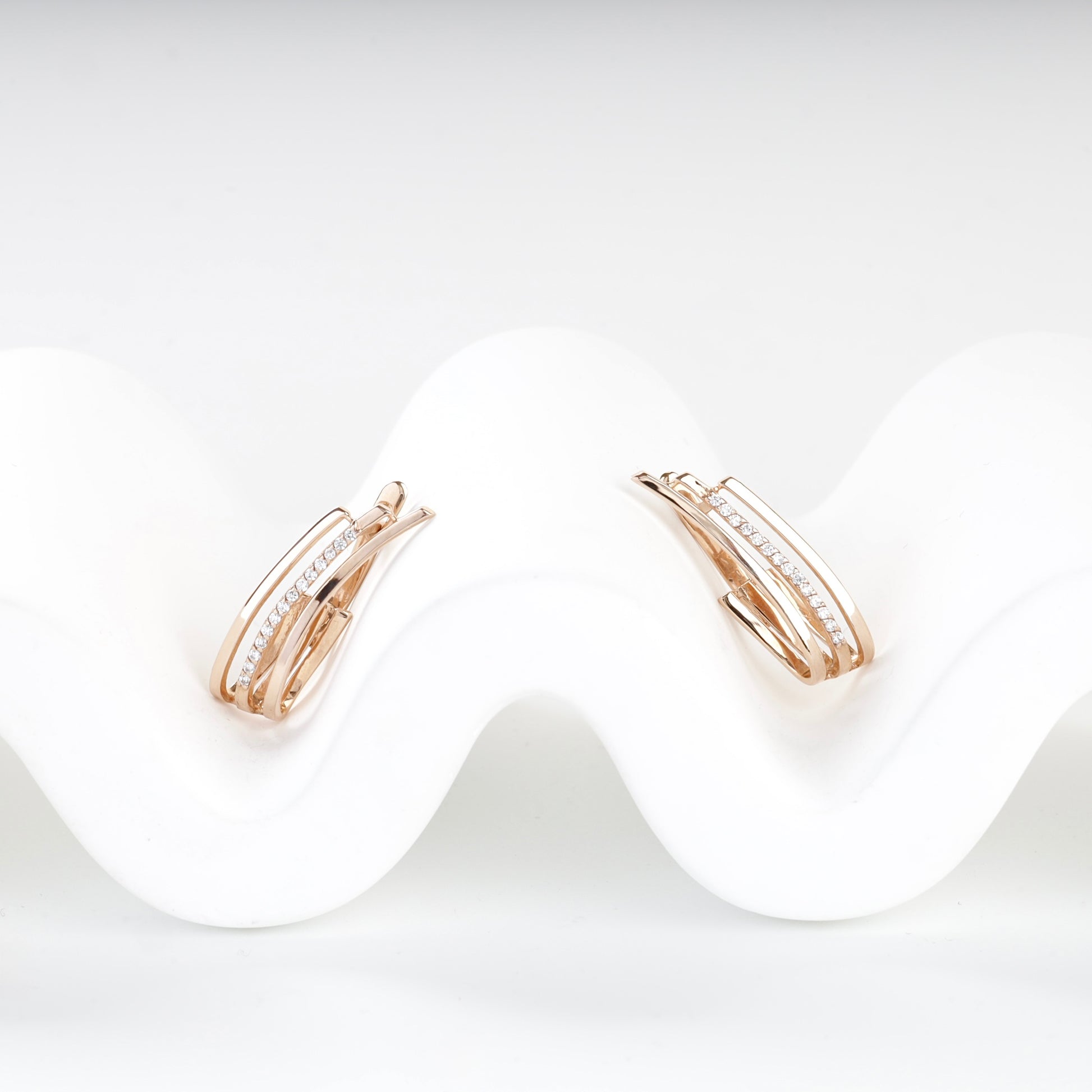 Cubic zirconia triple-band rose gold earrings, angled view