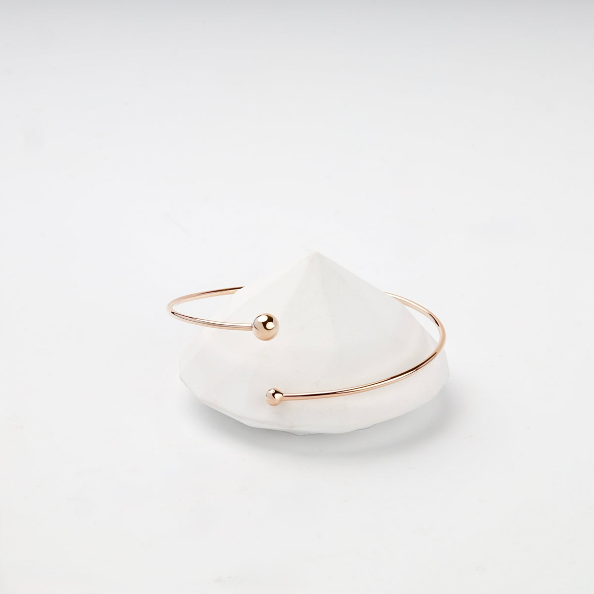 Asymmetric ball-end rose gold cuff bracelet close-up