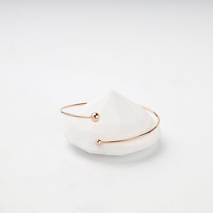 Asymmetric ball-end rose gold cuff bracelet close-up