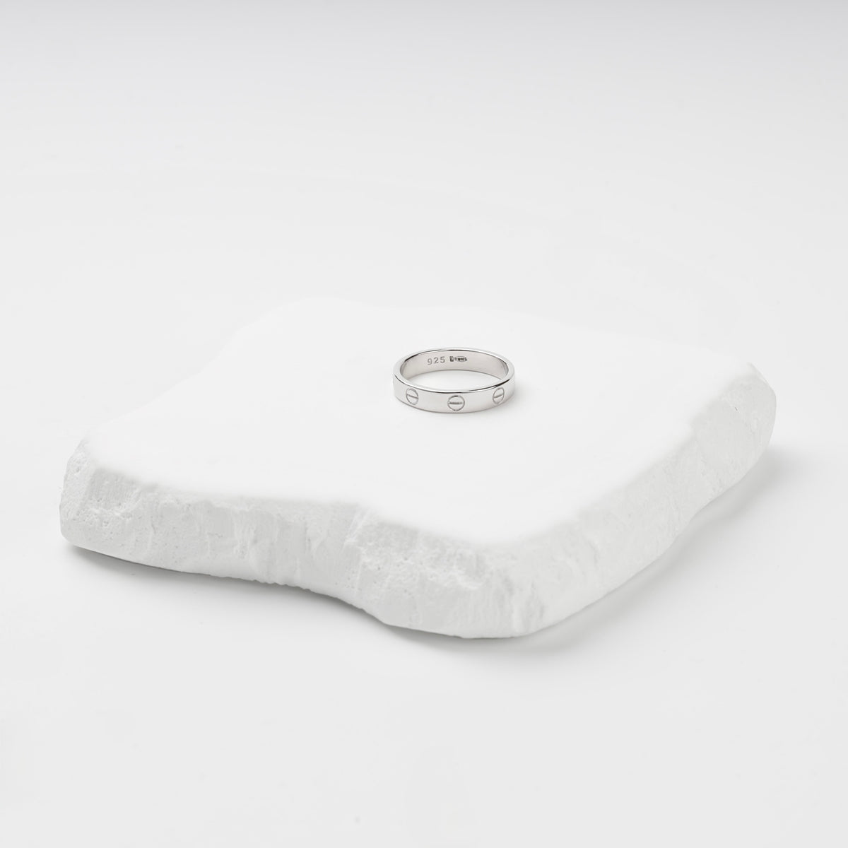 Angled view of the rhodium-plated screw motif ring and its smooth interior