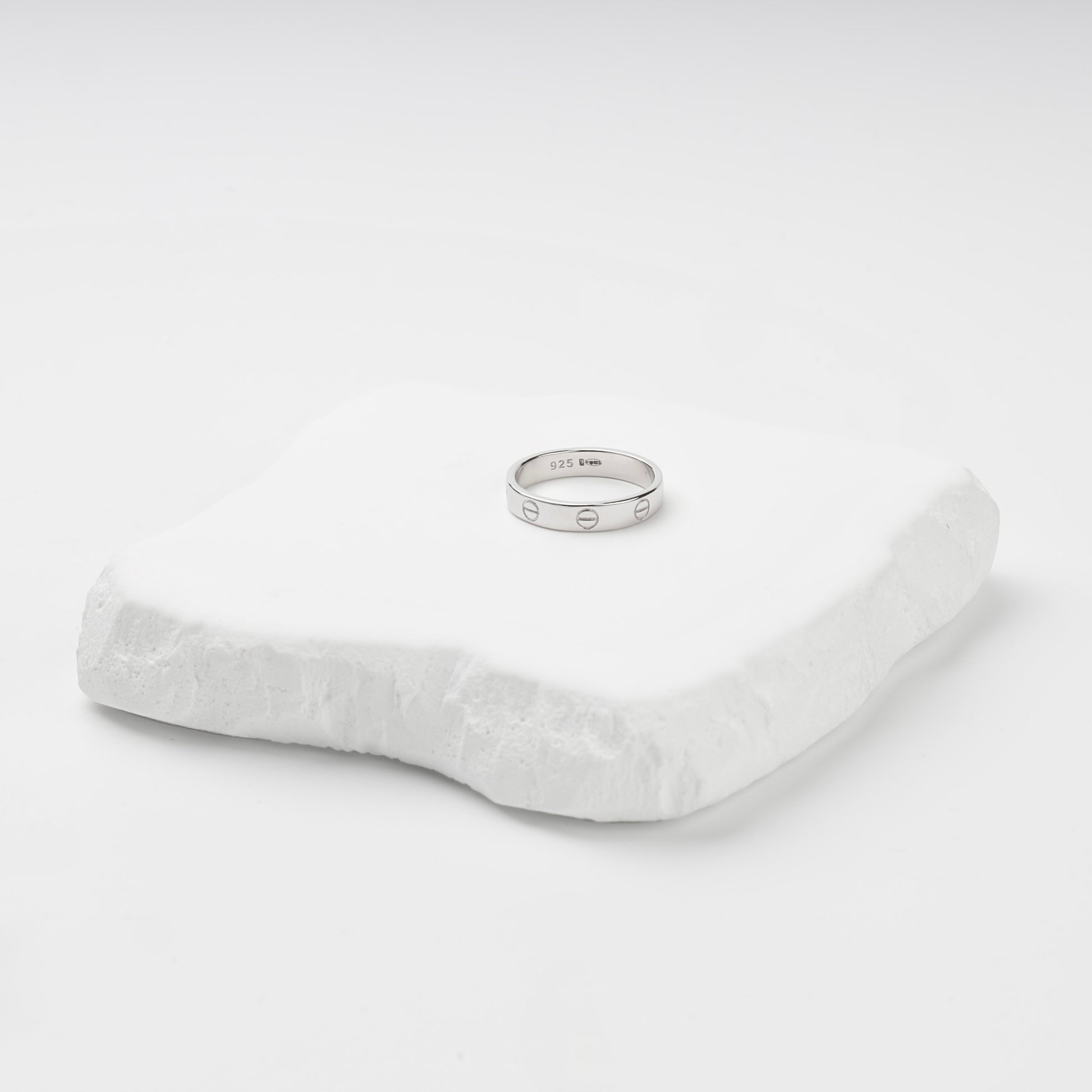 Angled view of the rhodium-plated screw motif ring and its smooth interior