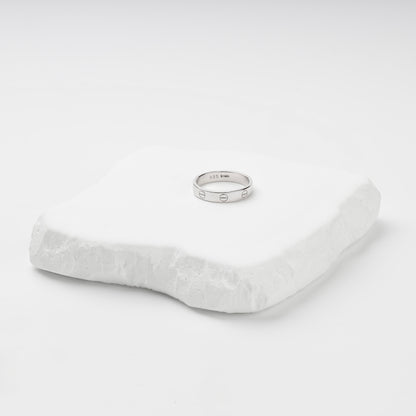 Angled view of the rhodium-plated screw motif ring and its smooth interior