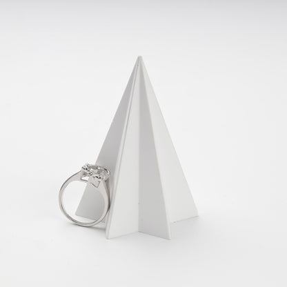 Silver cubic zirconia ring displayed beside a white geometric stand