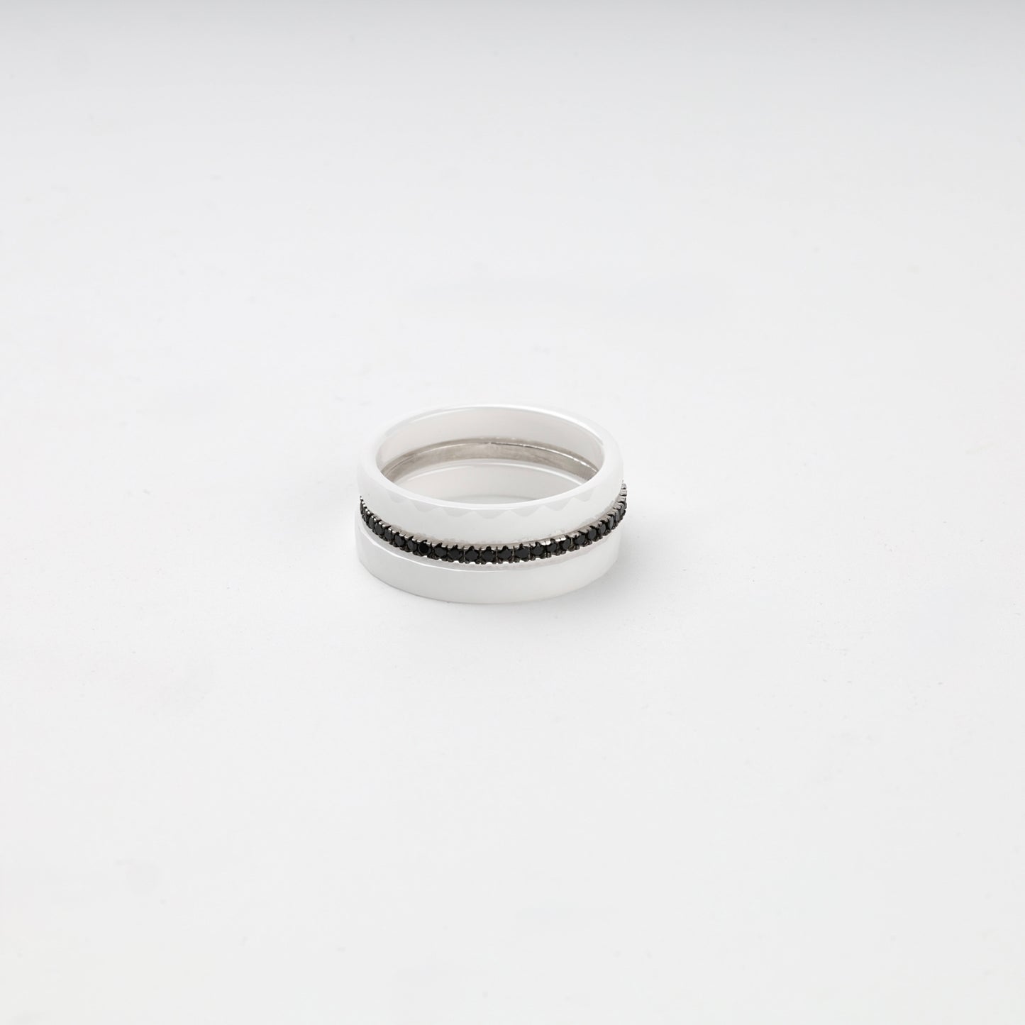 Faceted white ceramic three-ring set with a single row of black cubic zirconia