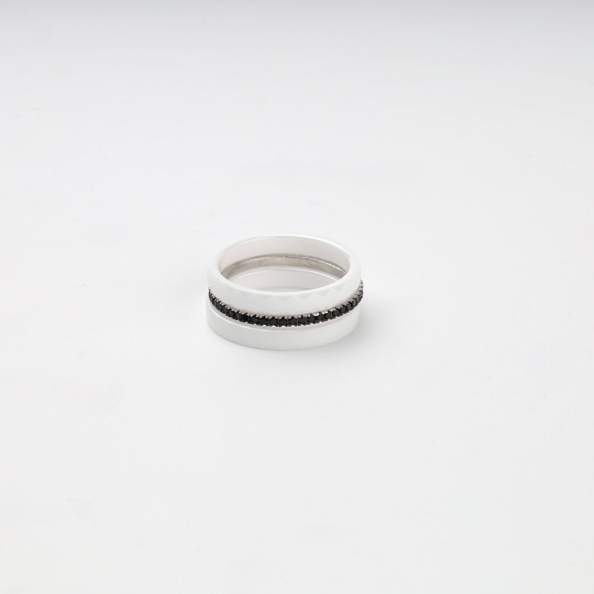 Faceted white ceramic three-ring set with a single row of black cubic zirconia