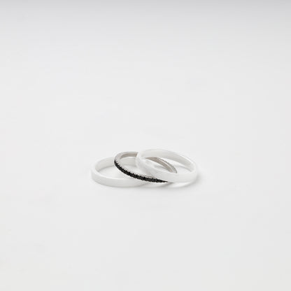 White ceramic ring set arranged around a black cubic zirconia center band