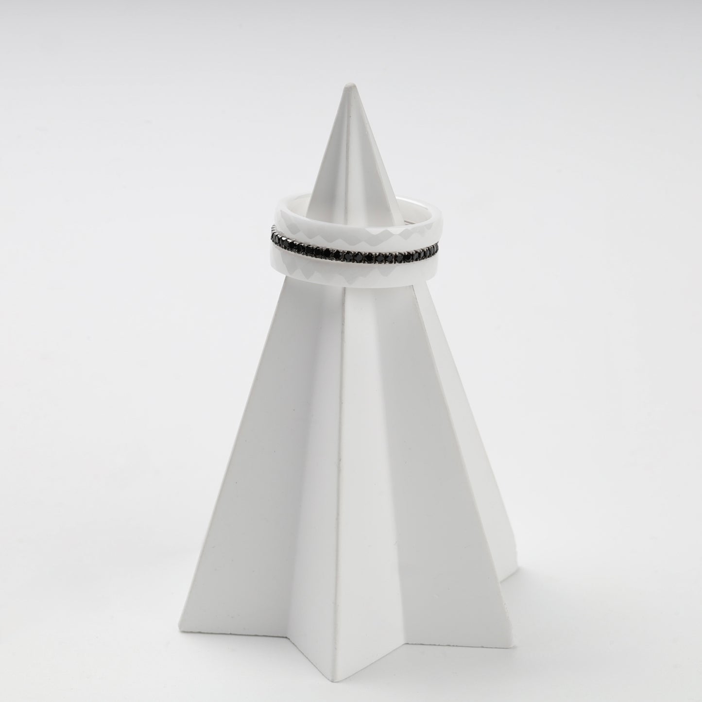 Faceted white ceramic and black cubic zirconia rings in a layered arrangement