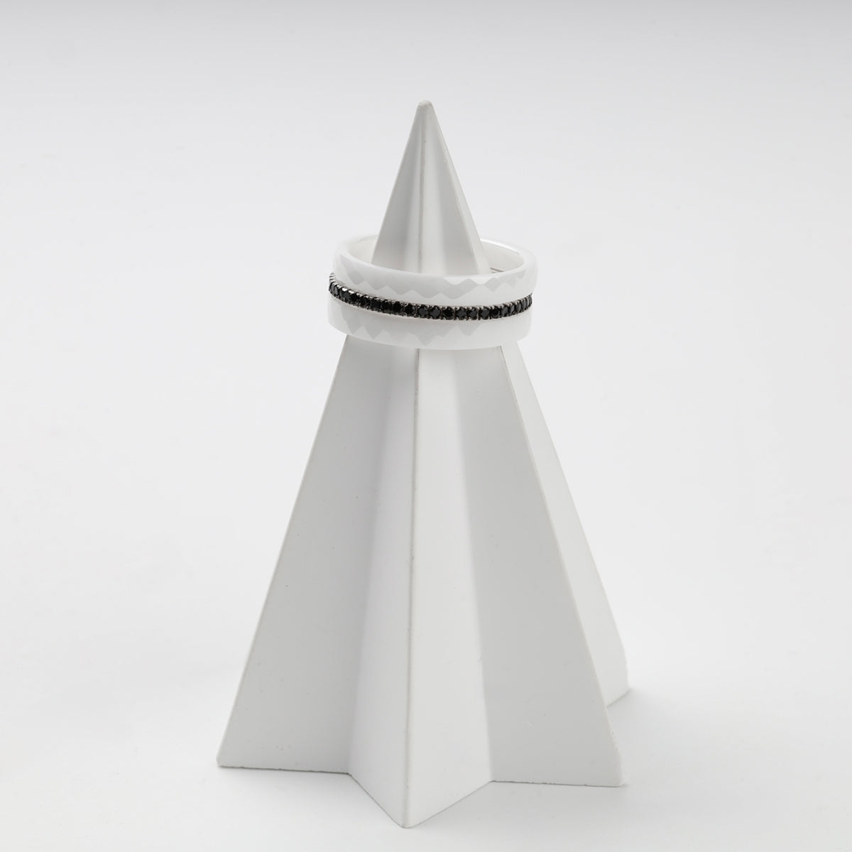 Faceted white ceramic and black cubic zirconia rings in a layered arrangement