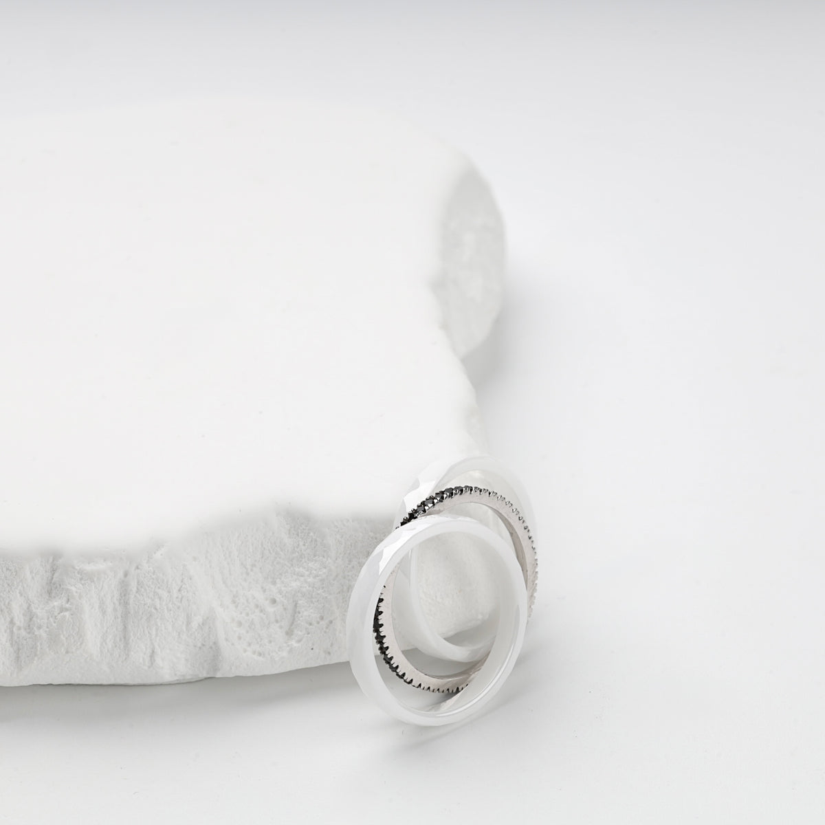 Three-ring white ceramic set displayed on a white geometric stand