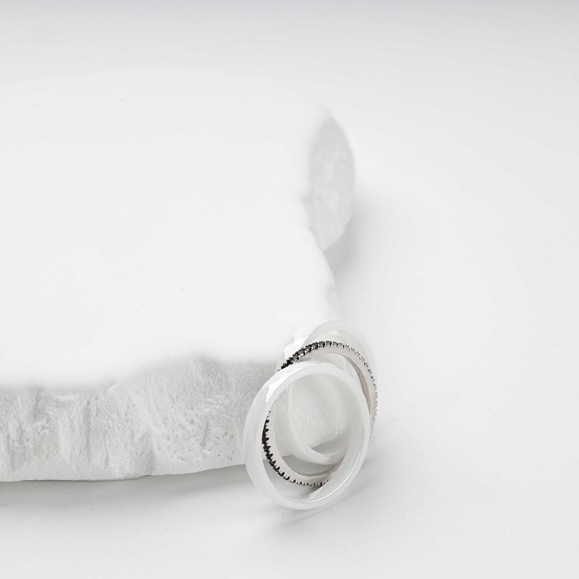 Three-ring white ceramic set displayed on a white geometric stand