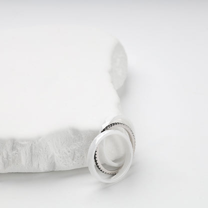Three-ring white ceramic set displayed on a white geometric stand