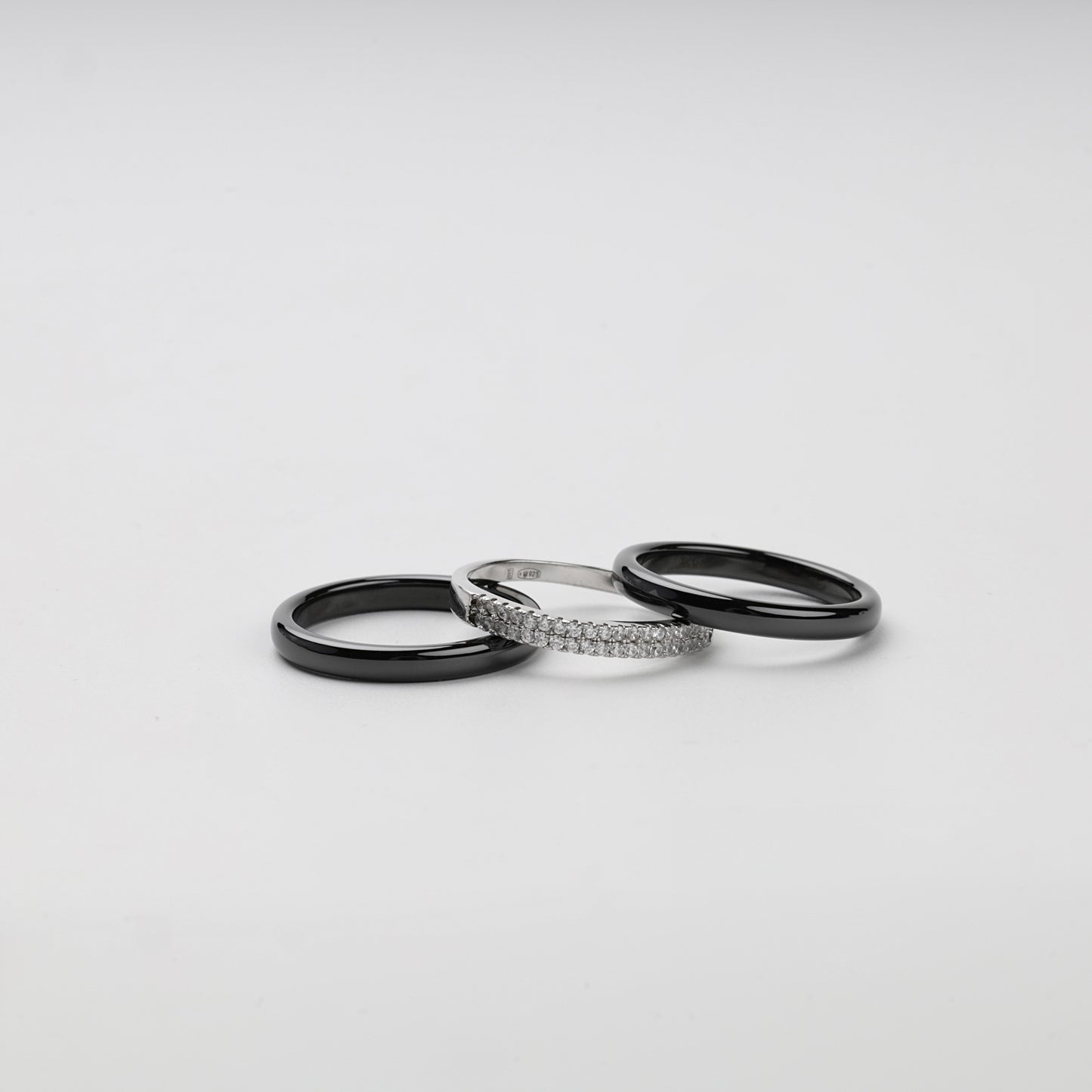 Front angle of a black ceramic three-ring set with clear cubic zirconia