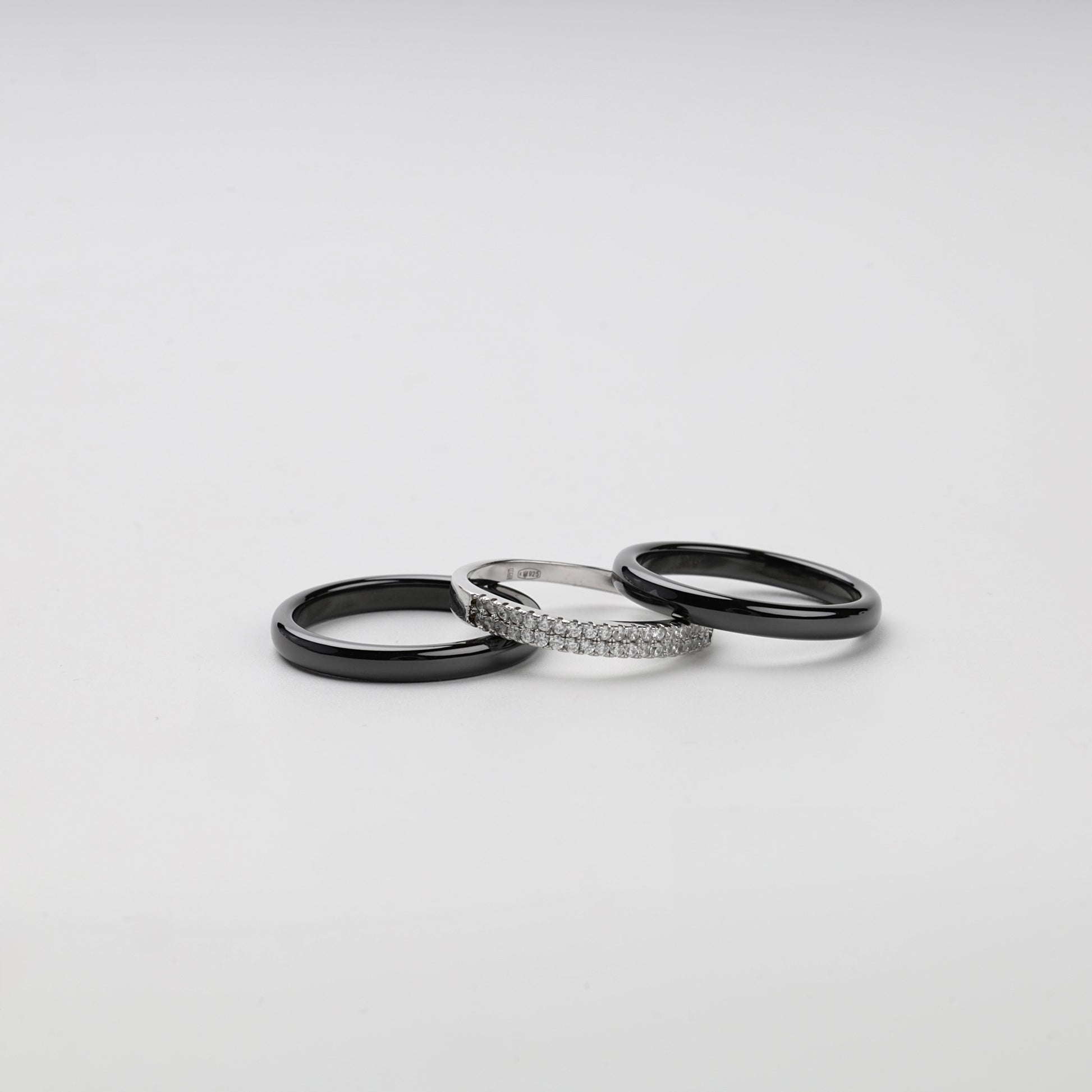 Front angle of a black ceramic three-ring set with clear cubic zirconia
