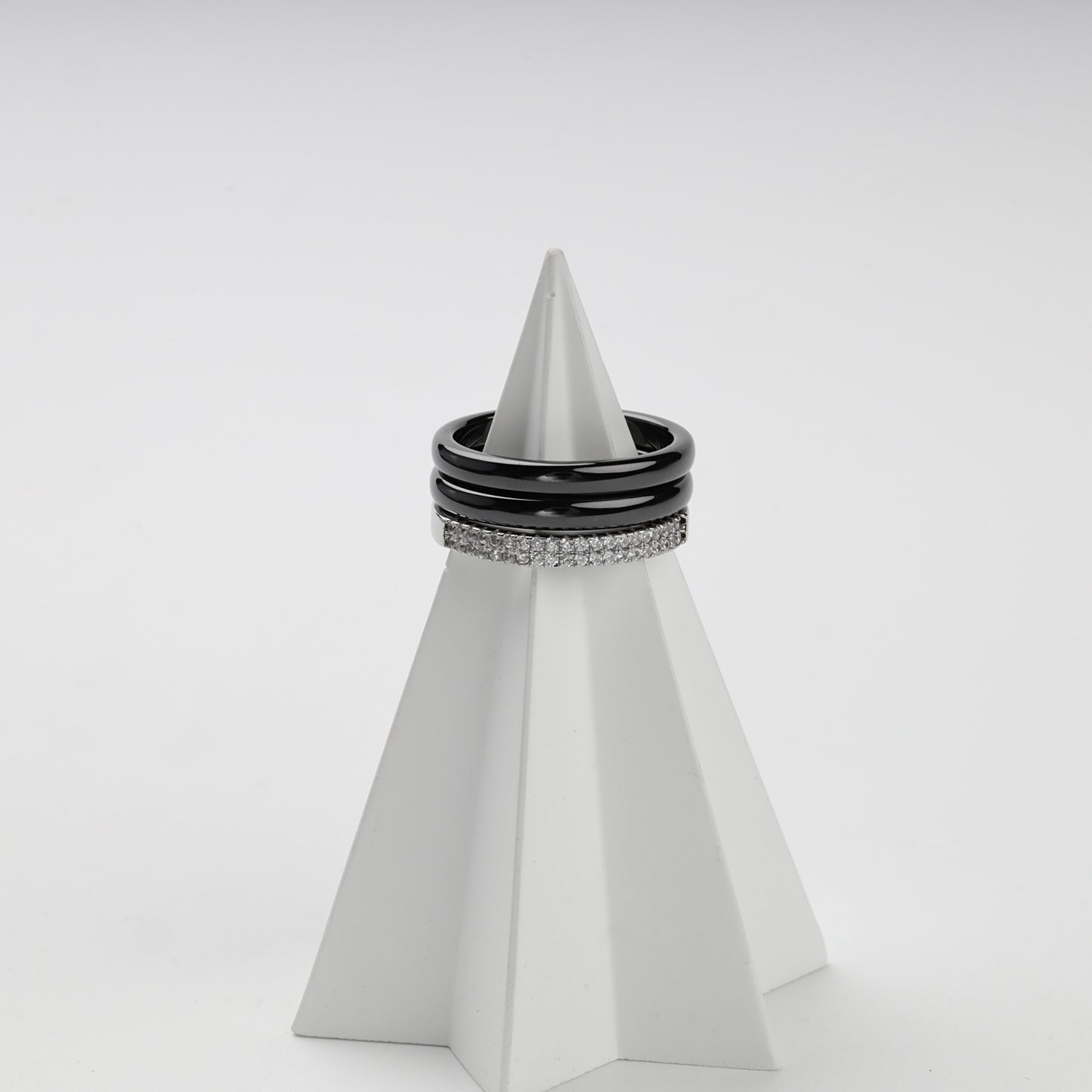 Stacked view of two black ceramic rings and a double-row cubic zirconia ring