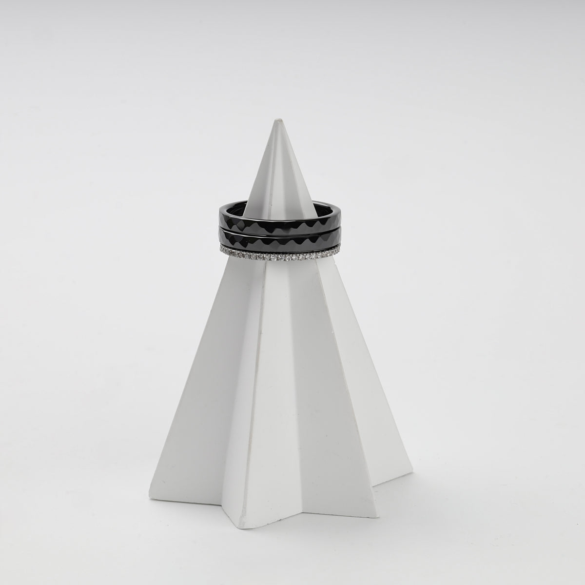 Three-ring black ceramic and clear cubic zirconia set on a white stand