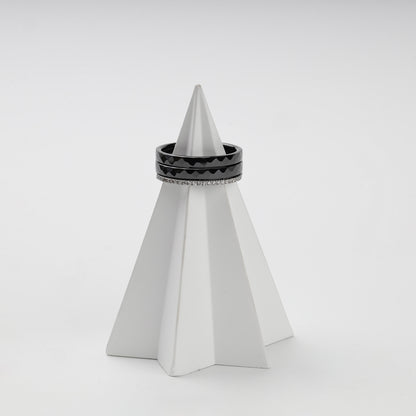 Three-ring black ceramic and clear cubic zirconia set on a white stand