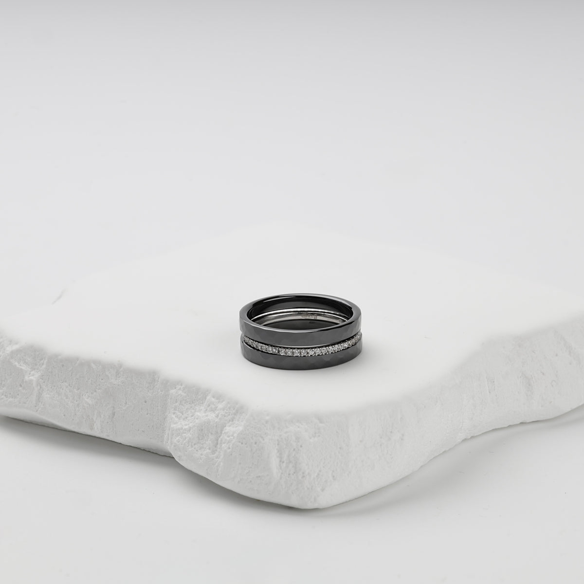 Faceted black ceramic three-ring set with a single row of clear cubic zirconia